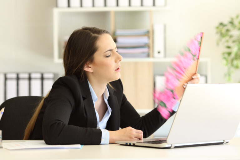 Overwhelmed businesswoman suffering heat stroke at office