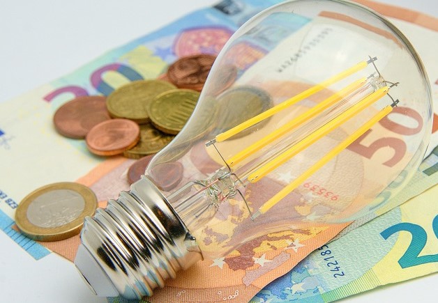 House energy cost theme with euro banknotes, coins and bulb